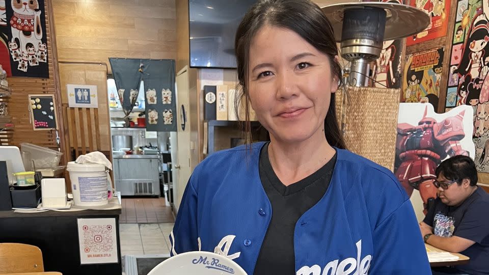 Hiroko Hinata, whose family owns Mr. Ramen, poses for a photo holding a bowl with Ohtani's Dodgers jersey number on it. - Natasha Chen/CNN
