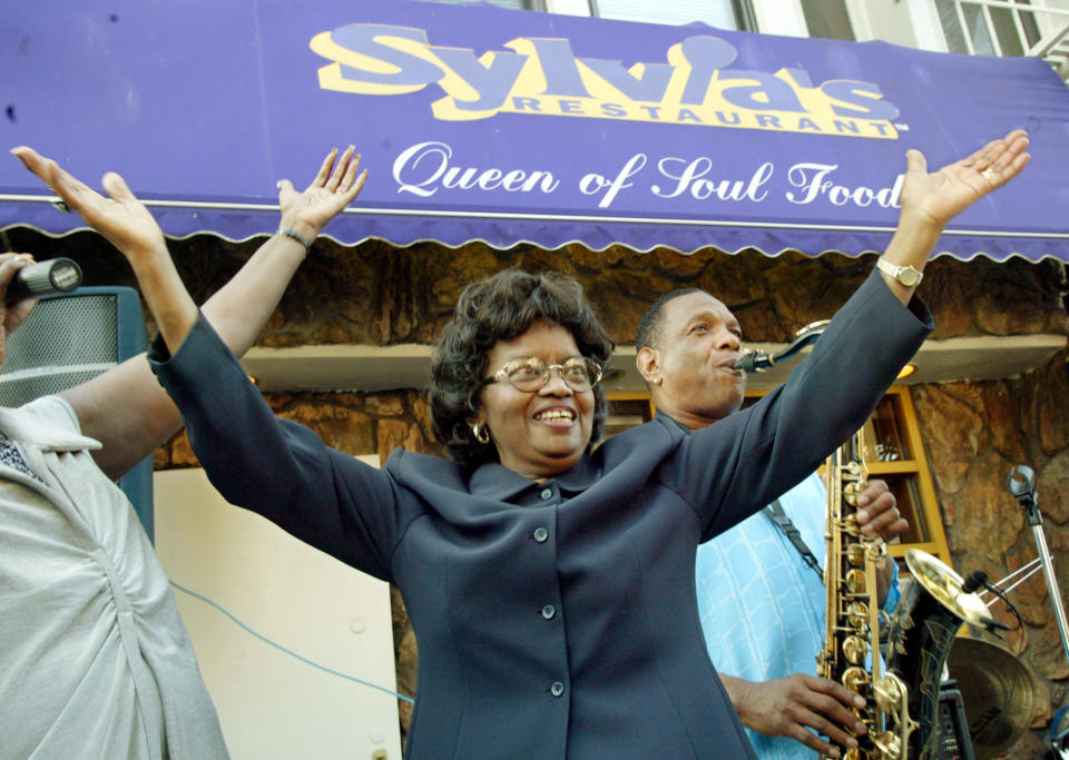 FILE- In this Aug. 1, 2002 file photo, Sylvia Woods, center, moves to the music outside her restaurant, “Sylvia's,” during the restaurant's 40th anniversary celebration, in the Harlem neighborhood of New York. Woods died in Mount Vernon, N.Y. on Thursday, July 19, 2012. She was 86. (AP Photo/Stuart Ramson, File)