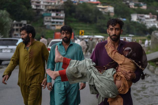 A man carries his sick daughter along a road damaged by flood waters following heavy monsoon rains in Madian area in Pakistan's northern Swat Valley on Aug. 27, 2022. (Photo: ABDUL MAJEED/AFP/Getty Images)