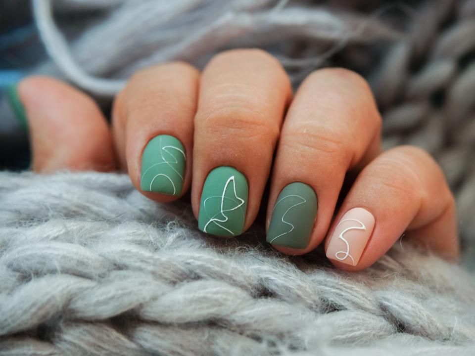 Green manicure with minimalistic line designs.