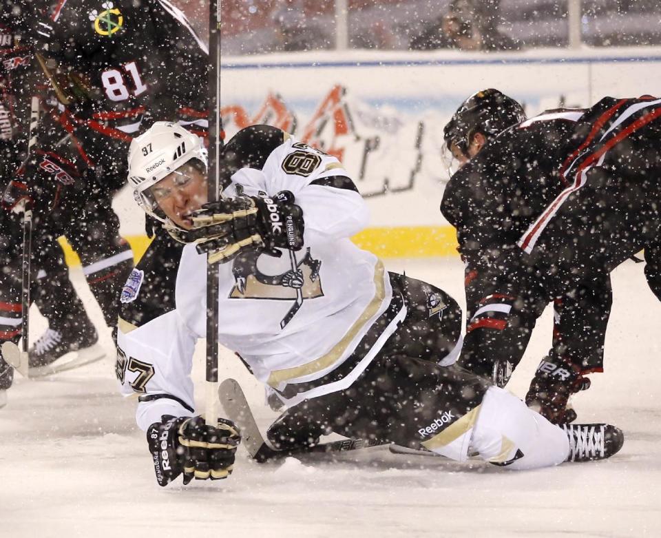 Pittsburgh Penguins center Sidney Crosby (87) falls to the ice after being checked by Chicago Blackhawks center Jonathan Toews, right, during the first period of an NHL Stadium Series hockey game at Soldier Field on Saturday, March 1, 2014, in Chicago. (AP Photo/Charles Rex Arbogast)