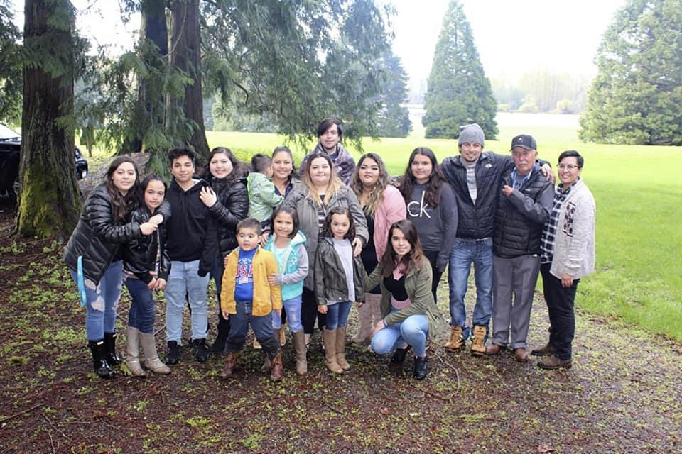 In this undated photo provided by Melissa Espinoza, Raul Espinoza Gomez, second from right, poses for a photo at Remlinger Farms, in Carnation, Wash., where the majority of the family works. He’s pictured with some of his 22 grandchildren and great-grandchildren. Gomez has an appointment Saturday, March 6, 2021, for his second dose of coronavirus vaccine and by Easter, the 77-year-old's immune system will be ready to protect him from the virus. But how the family celebrates will depend on government advice, Melissa Espinoza said. (Melissa Espinoza via AP)