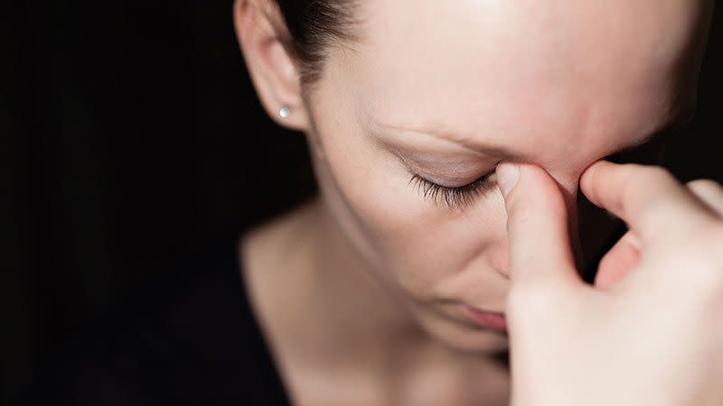 a person pinching the bridge of their nose in between their eyes, signaling stress