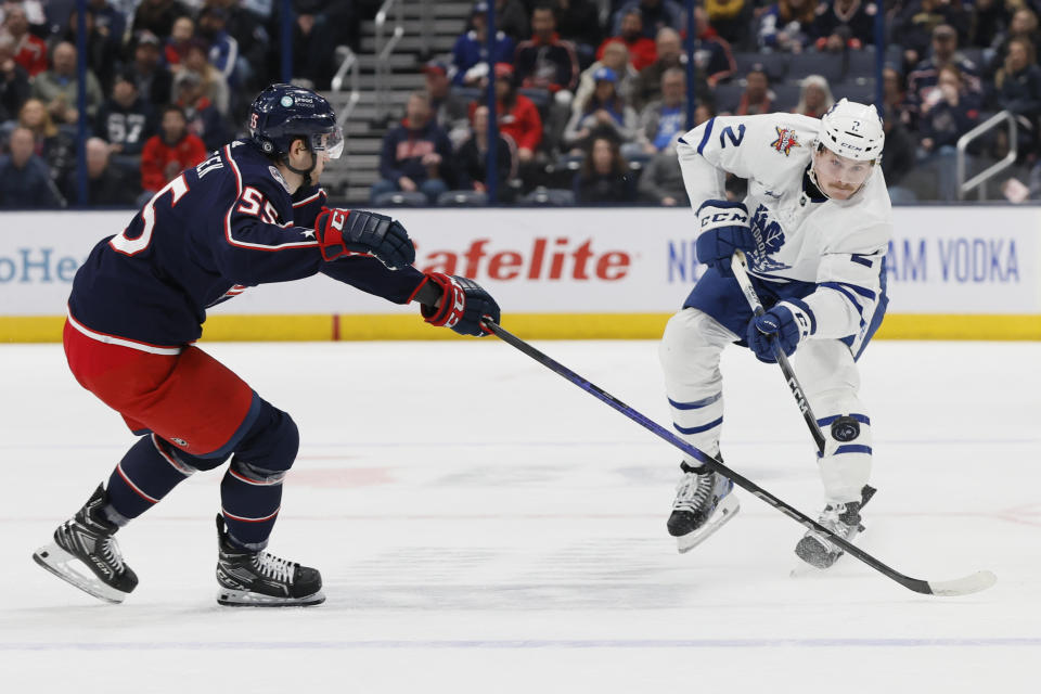 Toronto Maple Leafs' Simon Benoit, right, passes the puck across the blue line as Columbus Blue Jackets' David Jiricek defends during the first period of an NHL hockey game Friday, Dec. 29, 2023, in Columbus, Ohio. (AP Photo/Jay LaPrete)