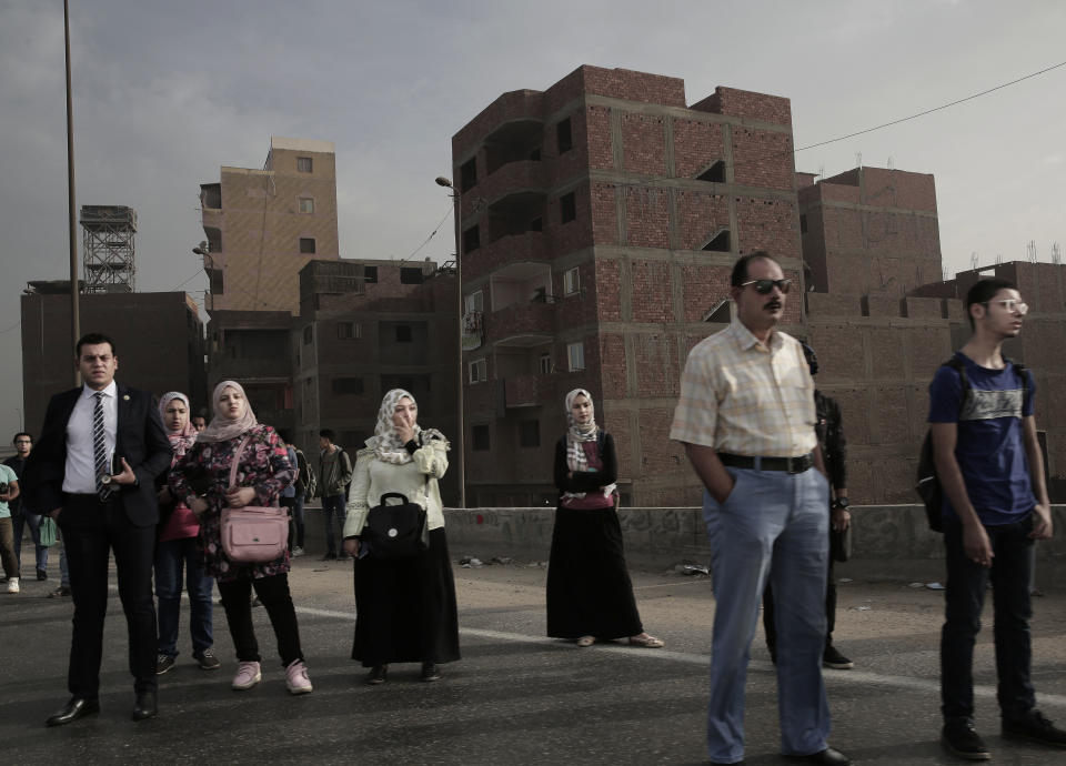 People wait for an early morning bus on the ring road, in Cairo, Egypt, Oct. 23, 2018. A city of 20 million people that combines charm and squalor, Cairo may soon witness an exodus by some of its well-heeled residents, state employees and foreign embassies to a new capital. The government argues that Cairo is already bursting at the seams and will grow to 40 million by 2050. (AP Photo/Nariman El-Mofty)