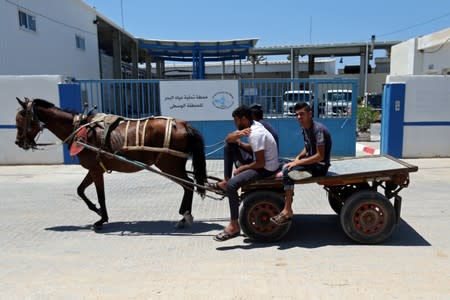 Palestinians ride a horse-drawn cart past Gaza desalination plant, in the central Gaza Strip