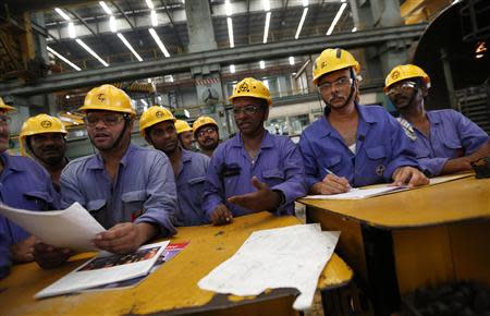 Employees check papers during their meeting after their lunch break inside the heavy electrical manufacturing unit of Larsen & Turbo in Mumbai December 4, 2013. REUTERS/Mansi Thapliyal