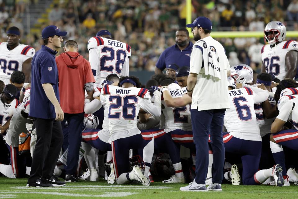 New England Patriots players kneel after cornerback Isaiah Bolden was injured during the second half of a preseason NFL football game against the Green Bay Packers, Saturday, Aug. 19, 2023, in Green Bay, Wis. The game was suspended after the injury. (AP Photo/Matt Ludtke)