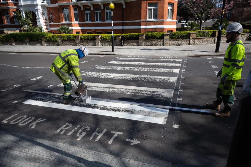 LONDON, ENGLAND - MARCH 24: A Highways Maintenance team takes advantage of the COVID-19 coronavirus lockdown and quiet streets to re-paint the iconic Abbey Road crossing on March 24, 2020 in London, England. The Beatles made the pedestrian crossing famous after featuring a photograph of the group walking on it, near to Abbey Road Studios. The album and connected artwork celebrated its fiftieth anniversary last year. British Prime Minister, Boris Johnson, announced strict lockdown measures urging people to stay at home and only leave the house for basic food shopping, exercise once a day and essential travel to and from work. The Coronavirus (COVID-19) pandemic has spread to at least 182 countries, claiming over 10,000 lives and infecting hundreds of thousands more. (Photo by Leon Neal/Getty Images)