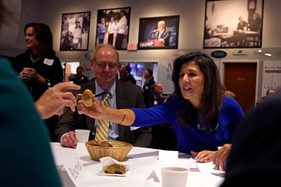 Republican presidential candidate Nikki Haley passes an autographed wooden egg to a guest during a breakfast gathering at Saint Anselm College, Wednesday, May 24, 2023, in Manchester, N.H.