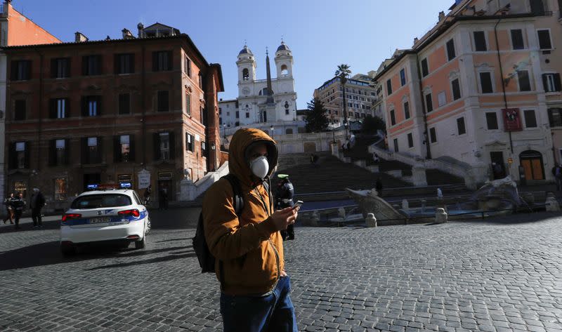 A man wearing a protective face mask walks near the Rome's Spanish Steps, virtually deserted after a decree orders for the whole of Italy to be on lockdown in an unprecedented clampdown aimed at beating the coronavirus, in Rome