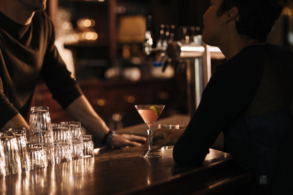 A bartender serving a pink drink to a customer