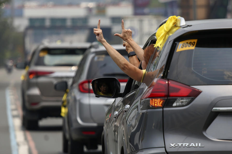 Supporters of former Philippine President Benigno Aquino III flash the "L" sign meaning "Fight!" from a vehicle window during a motorcade before his burial in Quezon City, Philippines on Saturday, June 26, 2021. Aquino was buried in austere state rites during the pandemic Saturday with many remembering him for standing up to China over territorial disputes, striking a peace deal with Muslim guerrillas and defending democracy in a Southeast Asian nation where his parents helped topple a dictator. He was 61. (AP Photo/Basilio Sepe)