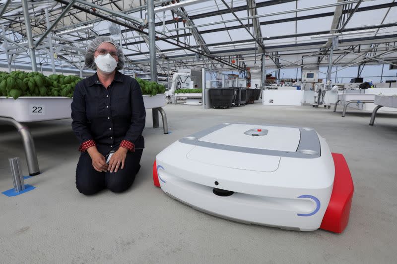 Sarah Osentoski, senior vice president of engineering at Iron Ox, kneels next to the self-driving robot Grover at the Silicon Valley company's greenhouse in Gilroy, California