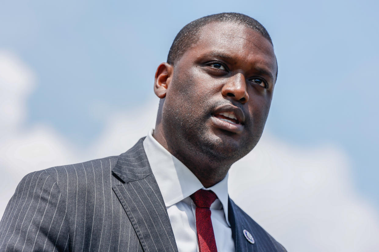 Rep. Mondaire Jones stands against a blue sky.