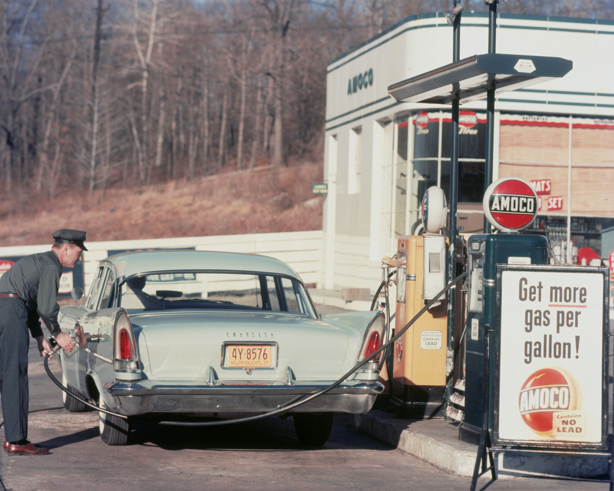 A petrol pump attendant filling up a Chrysler car at an Amoco station, 1958.