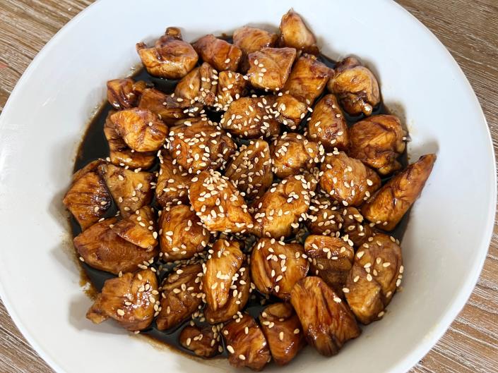 A bowl of teriyaki chicken with sesame seeds in white bowl