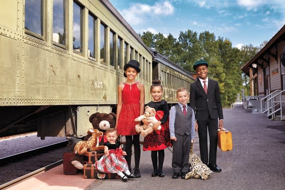 A group of children are dressed in holiday clothes in front of a train.