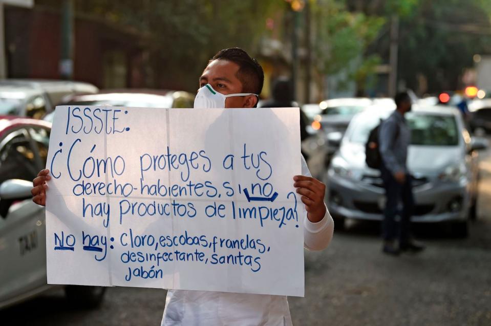 A health worker of the Tacuba General Hospital holds a sign reading How do you protect rights-holders if there are no cleaning products? There are no: chlorine, brooms, cleaning cloths, disinfectants, cleaning paper, soap during a demonstration for the lack of medical material to care for COVID-9 patients, in Mexico City on April 21.