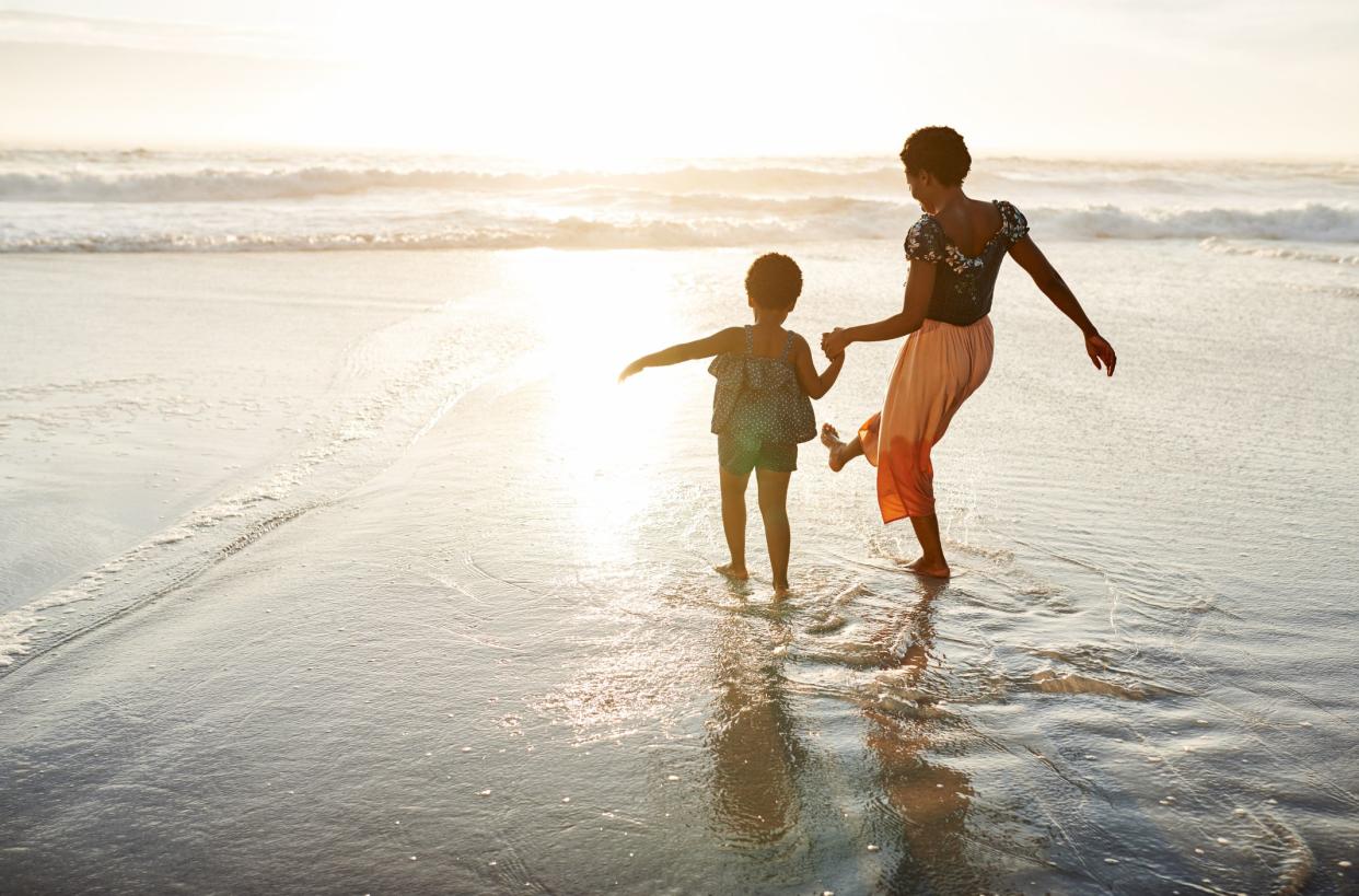 Shot of a young woman spending time at the beach with her adorable daughter