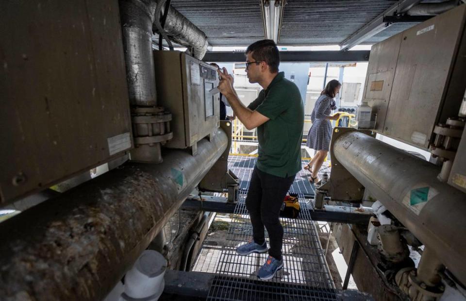 Undergraduate student and member of UM’s Industrial Assessment Center Team, Afshin Asadi, center, photographs the specs on one of the chillers on the roof of 550 Biltmore Way.