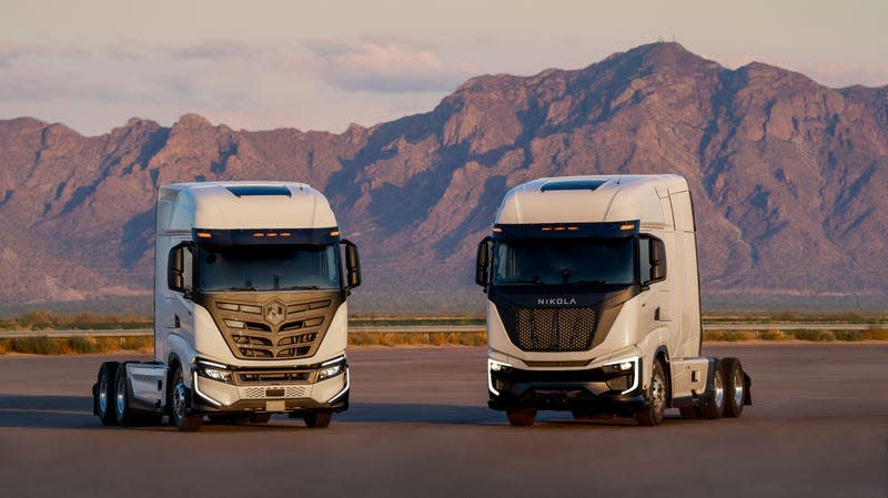 Two of Nikola's semi-truck side-by-side in an empty lot with mountains in the background