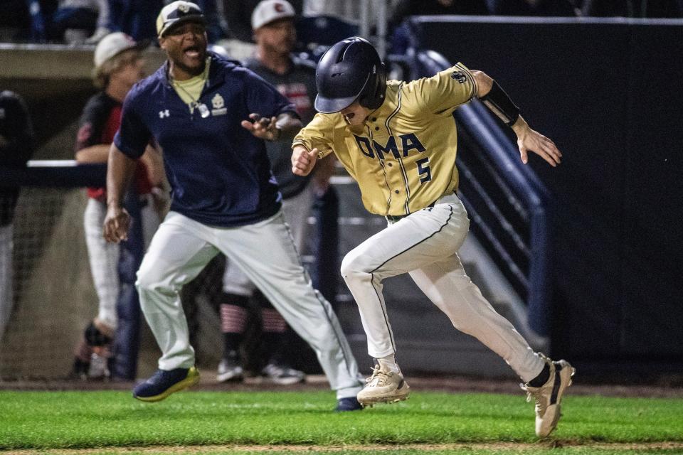Delaware Military Academy junior Dylan Delcollo (5) scores a run while head coach Aaron Lewis provides encouragement during the DMA vs. Conrad DIAA Baseball championship game at Frawley Stadium in Wilmington on Saturday, June 3, 2023. DMA won 7-1.