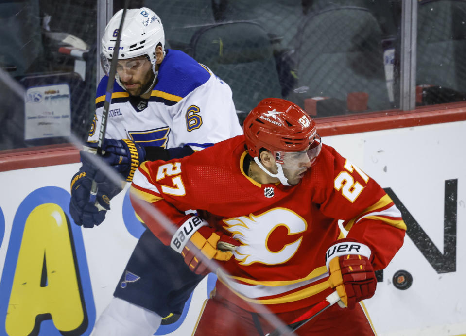 St. Louis Blues defenseman Marco Scandella, left, and Calgary Flames forward Matthew Coronato (27) chase the puck during third-period NHL hockey game action in Calgary, Alberta, Thursday, Oct. 26, 2023. (Jeff McIntosh/The Canadian Press via AP)