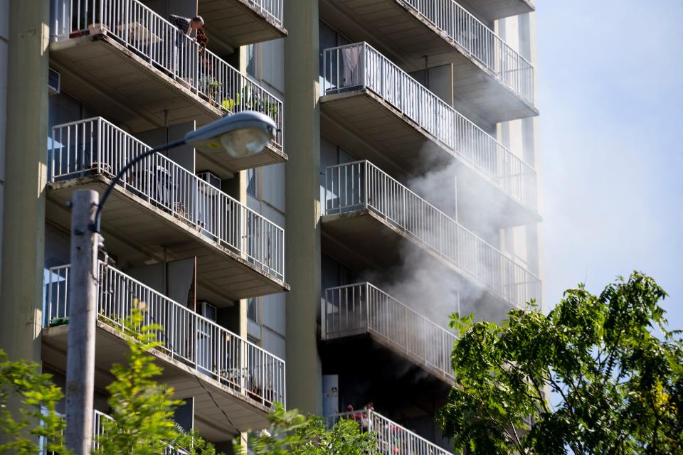 A man looks down from his balcony as smoke pours out of an apartment below at Bryton Tower in Memphis, Tenn., on Friday, September 15, 2023.