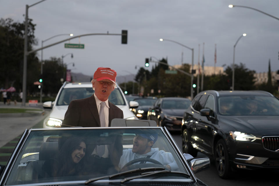 Two supporters of President Donald Trump laugh while sitting in a car with a cutout of Trump at a rally in Beverly Hills, Calif., Saturday, Oct. 24, 2020. (AP Photo/Jae C. Hong)