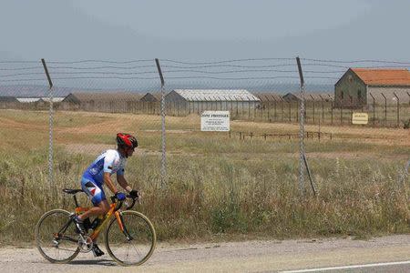 A cyclist looks at a military base in the southern French town of Miramas, near Marseille, France July 7, 2015. Explosives, 180 detonators and around 40 grenades were stolen from an army base in the southern French town of Miramas, near Marseille, a source close to investigation said on Tuesday. REUTERS/Philippe Laurenson