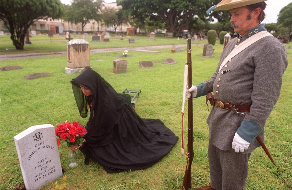 Kathy Clark of Lantana lays flowers at the newly placed grave of Confederate Capt. John Mizell as part of the ceremony for the Confederate Memorial Day at Woodlawn Cemetery. Mizell's second cousin and civil war re-enactor Lenny Albritton of West Palm Beach looks on. The Sons of Confederate Veterans visited 10 cemeteries, decorated graves and placed headstones on previously unmarked gravesites.
