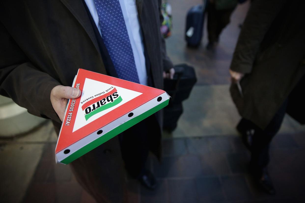 Amtrak passenger holds a box of Sbarro pizza as he is about to board a train at the Union Station March 10, 2014 in Washington, DC