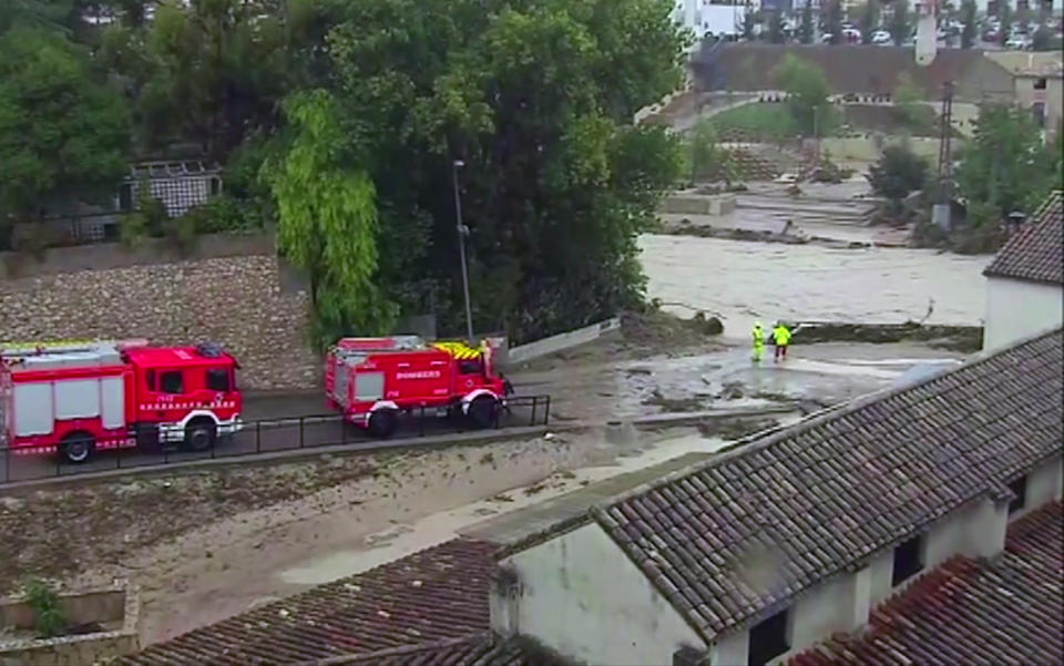 In this image made from video provided by Atlas, fire engines drive by a flooded river, in Ontiyente, Spain, Thursday, Sept. 12 2019. A large area of southeast Spain was battered Thursday by what was forecast to be its heaviest rainfall in more than a century, with the storms wreaking widespread destruction and killing at least two people. (Atlas via AP)