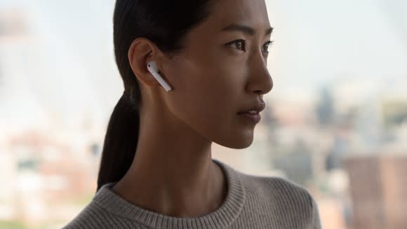 A woman wears AirPods in her ear in an Apple advertisement.