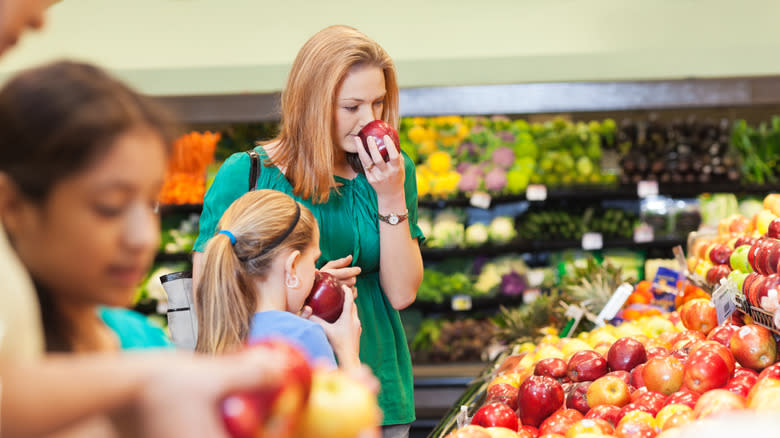 woman smelling apple at store