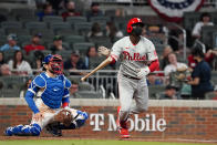 Philadelphia Phillies' Didi Gregorius (18) follows through on three-run home run as Atlanta Braves catcher Travis d'Arnaud (16) looks on in the fourth inning of a baseball game Sunday, April 11, 2021, in Atlanta. (AP Photo/John Bazemore)