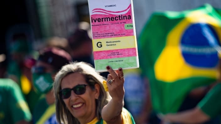 A supporter of Brazil President Jair Bolsonaro holds a large box of Ivermectin, used by many people there to treat COVID-19, during a May protest in Brasilia organized to show support of his government’s pandemic response. (Photo by Andressa Anholete/Getty Images)