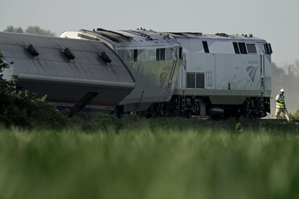 A worker inspects the scene of an Amtrak train which derailed after striking a dump truck, Monday, June 27, 2022, near Mendon, Mo. (AP Photo/Charlie Riedel)