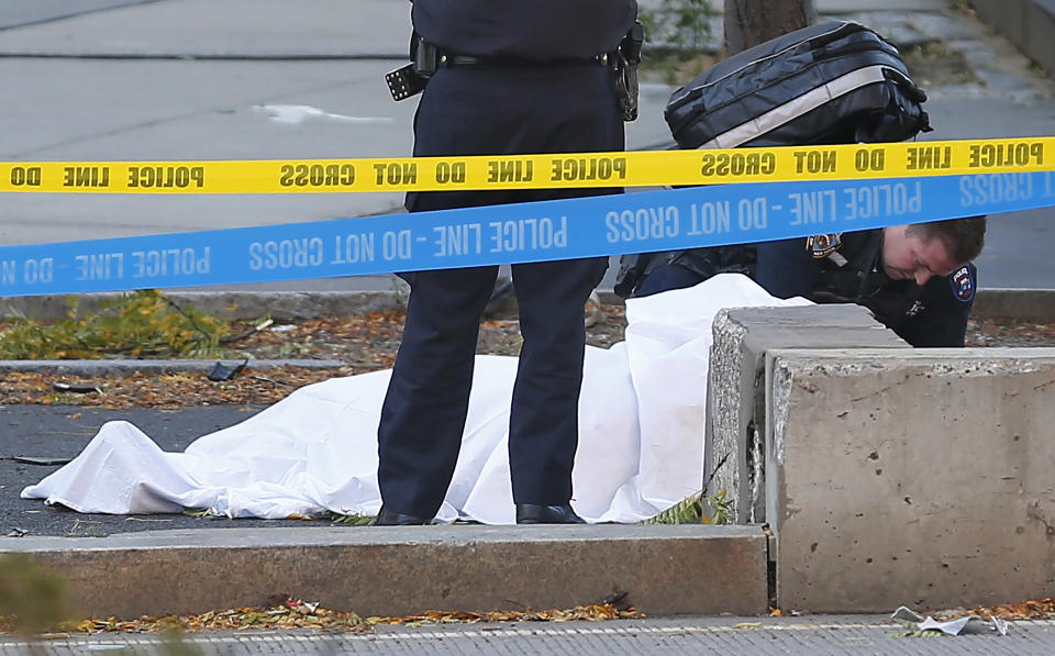 FILE - A paramedic looks at a body covered under a white sheet along a bike path, Oct. 31, 2017, in New York. Sayfullo Saipov, an Islamic extremist who killed eight in a New York bike path attack was convicted of federal crimes on Thursday, Jan. 26 2023, and could face the death penalty. (AP Photo/Bebeto Matthews, File)