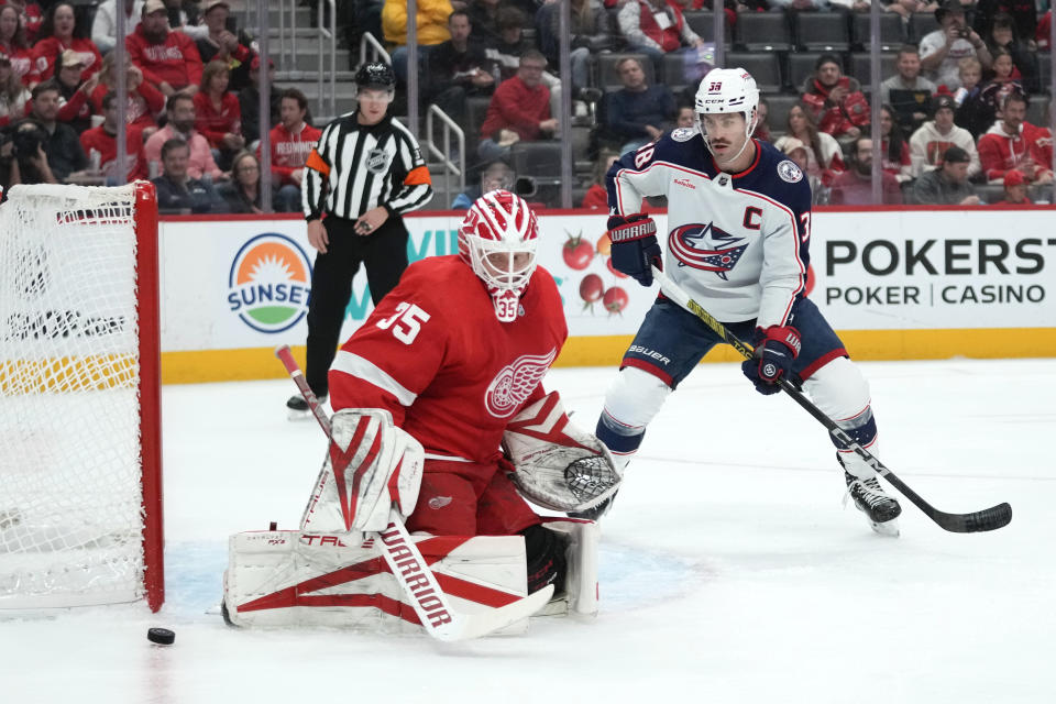 Detroit Red Wings goaltender Ville Husso (35) stops a shot as Columbus Blue Jackets center Boone Jenner (38) watches for a rebound in the first period of an NHL hockey game Saturday, Nov. 11, 2023, in Detroit. (AP Photo/Paul Sancya)