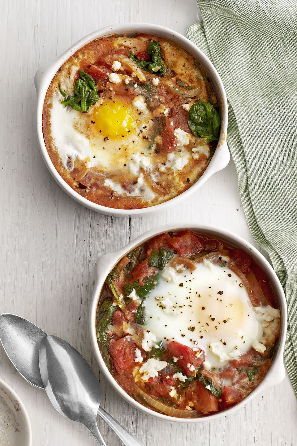 breakfast in bed baked eggs with spinach and tomato in bowls on table