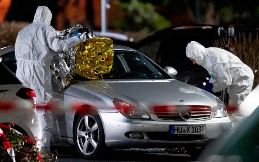 Police forensics officers search a Mercedes at one of the crime scenes - Michael Probst /AP