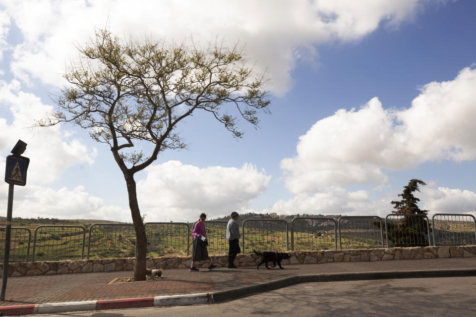 Two women walk their dogs in the West Bank Jewish settlement of Efrat, Friday, April 9, 2021. Israel went on an aggressive settlement spree during the Trump era, according to an AP investigation, pushing deeper into the occupied West Bank than ever before and putting the Biden administration into a bind as it seeks to revive Mideast peace efforts. (AP Photo/Maya Alleruzzo)