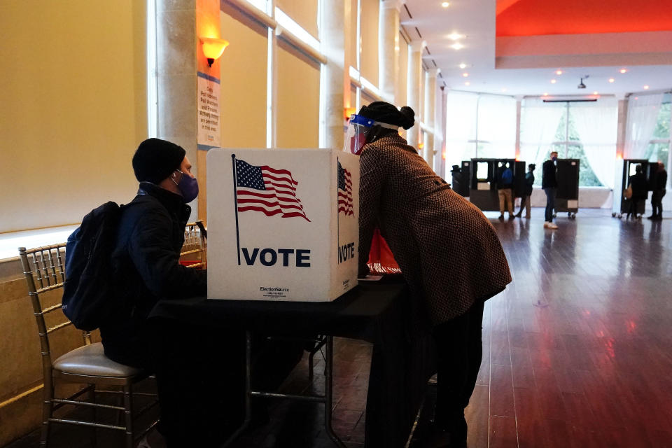 FILE - In this Nov. 3, 2020, file photo, a poll worker talks to a voter before they vote on a paper ballot on Election Day in Atlanta. The sweeping rewrite of Georgia's election rules that was signed into law by Republican Gov. Brian Kemp Thursday, March 25, 2021, represents the first big set of changes since former President Donald Trump's repeated, baseless claims of fraud following his presidential loss to Joe Biden. Georgia’s new, 98-page law makes numerous changes to how elections will be administered, including a new photo ID requirement for voting absentee by mail. (AP Photo/Brynn Anderson, File)