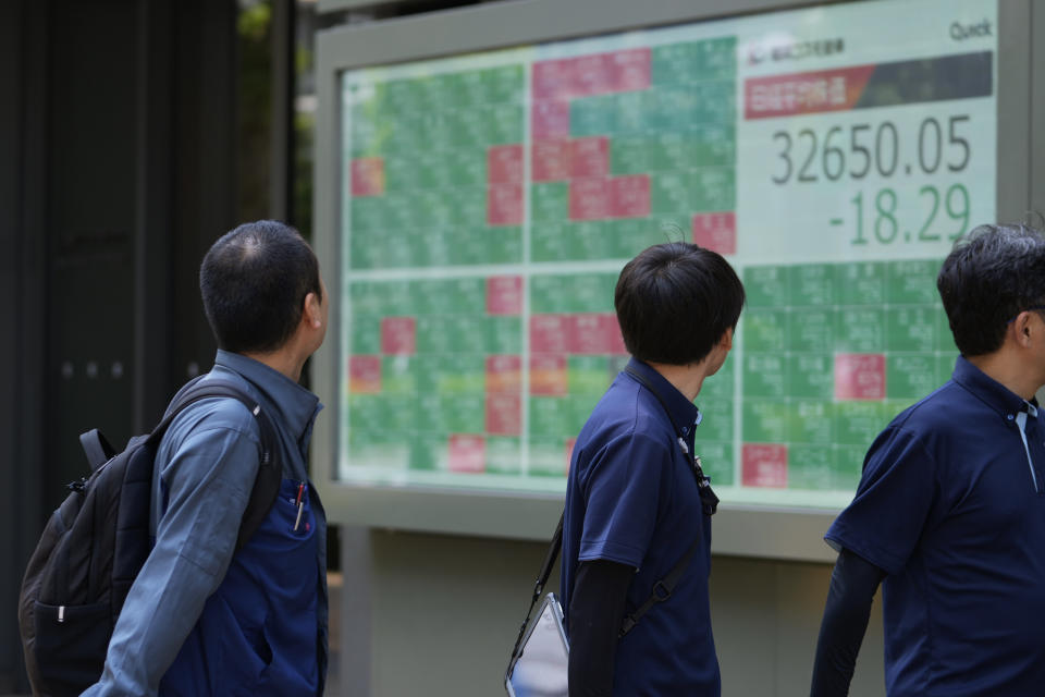 People walk by monitors showing Japan's Nikkei 225 index at a securities firm in Tokyo, Thursday, July 27, 2023. Asian shares were mixed on Friday after the Bank of Japan adjusted its bond purchase policy but kept its negative benchmark interest rate unchanged. (AP Photo/Hiro Komae)