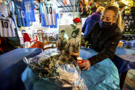 A woman lights a candle to honor soccer legend Diego Maradona, in Naples, Italy, Wednesday, Nov. 25, 2020. Diego Maradona has died. The Argentine soccer great was among the best players ever and who led his country to the 1986 World Cup title before later struggling with cocaine use and obesity. He was 60. (Alessandro Garofalo/LaPresse via AP)