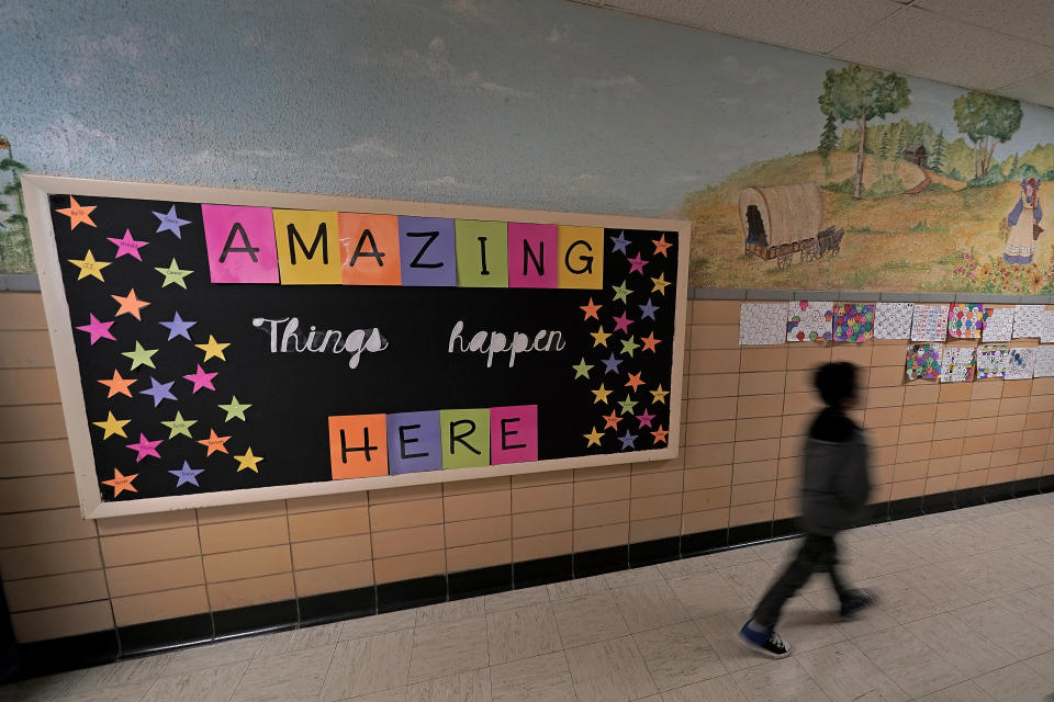 A third grader walks down a hall between classes at Highland Elementary School in Columbus, Kan., on Monday, Oct. 17, 2022. Third graders in the tiny 900-student Columbus school district have fought to catch up on reading in the wake of COVID-19 disruptions. (AP Photo/Charlie Riedel)