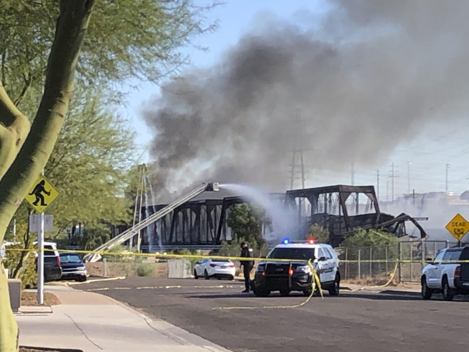 Firefighters respond to the scene of a train derailment in Tempe, Ariz.,Wednesday, July 29, 2020. Officials say a freight train traveling on a bridge that spans a lake in the Phoenix suburb derailed and set the bridge ablaze and partially collapsing the structure. There were no immediate reports of any leaks. (AP Photo/Ross D. Franklin)
