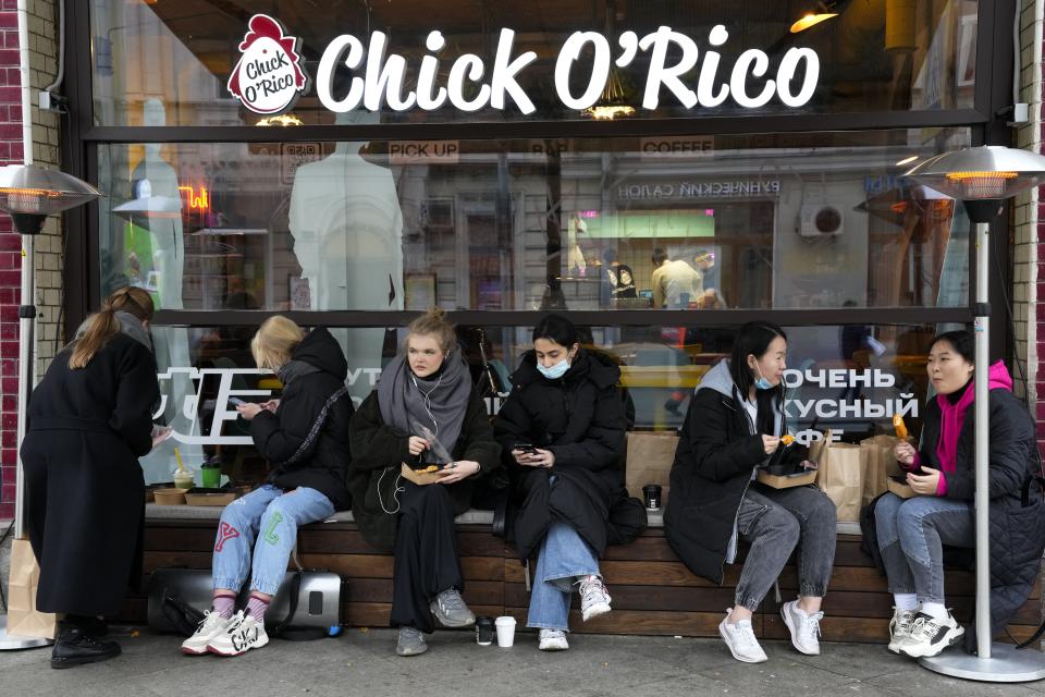 People eat their takeaway food sitting outside a cafe that is closed due to coronavirus in Moscow, Russia, Friday, Oct. 29, 2021. Russia on Friday recorded another record of daily COVID-19 deaths as authorities hoped to stem contagion by keeping most people off work. Moscow introduced the measure starting from Thursday, shutting kindergartens, schools, gyms, entertainment venues and most stores, and restricting restaurants and cafes to only takeout or delivery. (AP Photo/Alexander Zemlianichenko)
